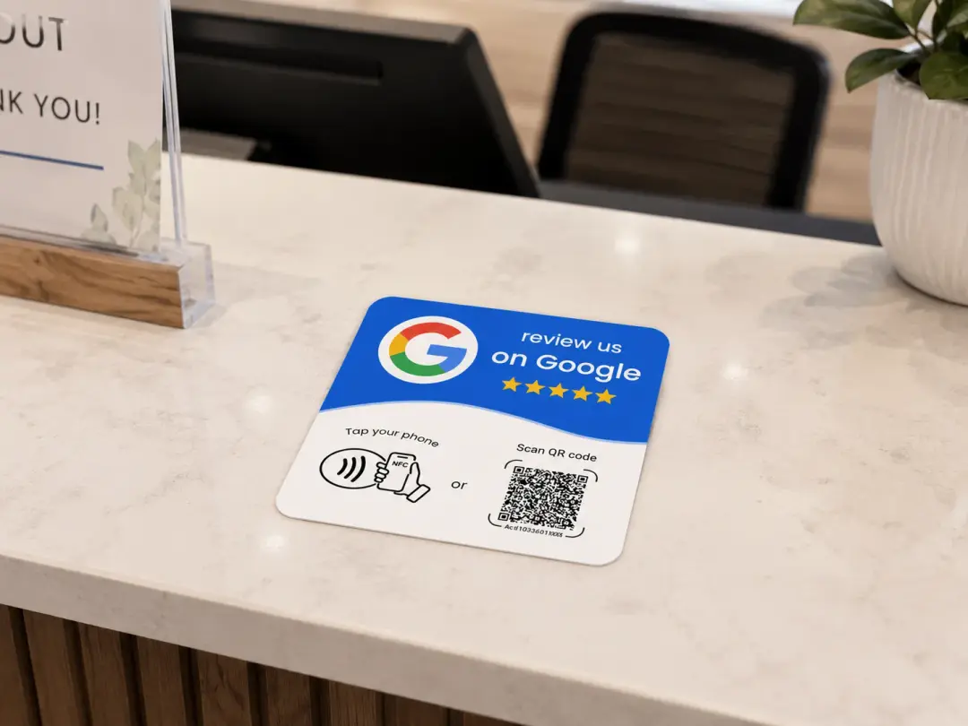 A review us on Google card on a shop counter, with a tap-your-phone NFC symbol and a QR code to scan.